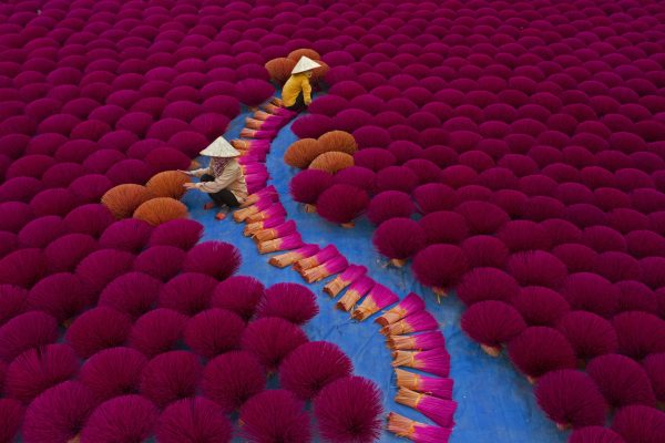 Vietnamese workers sit surrounded by thousands of incense sticks